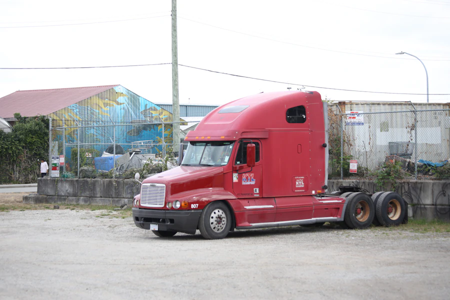 Red semi-truck cab parked in a gravel lot