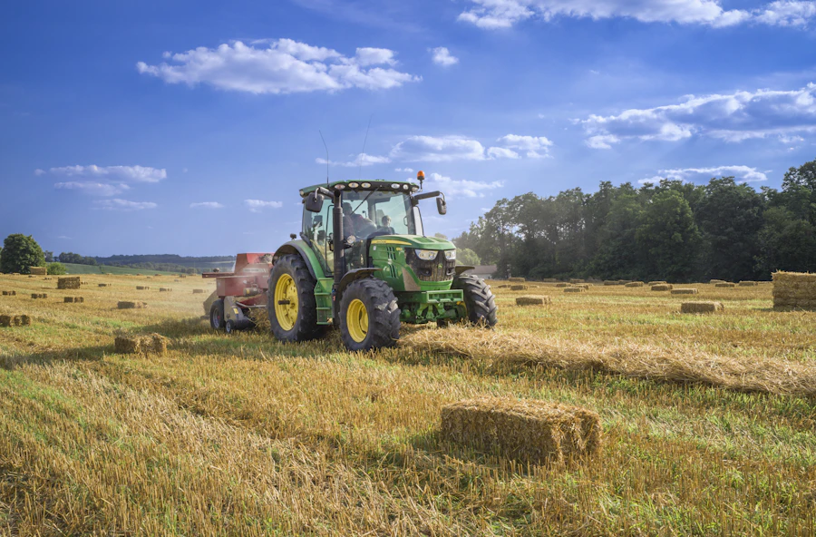 Green tractor baling hay in a field