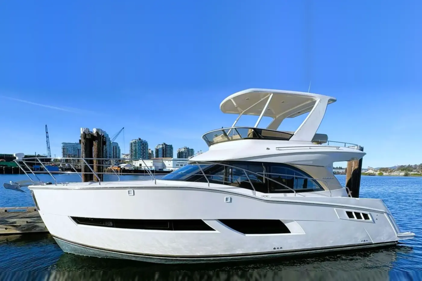 White flybridge motor yacht moored at a marina